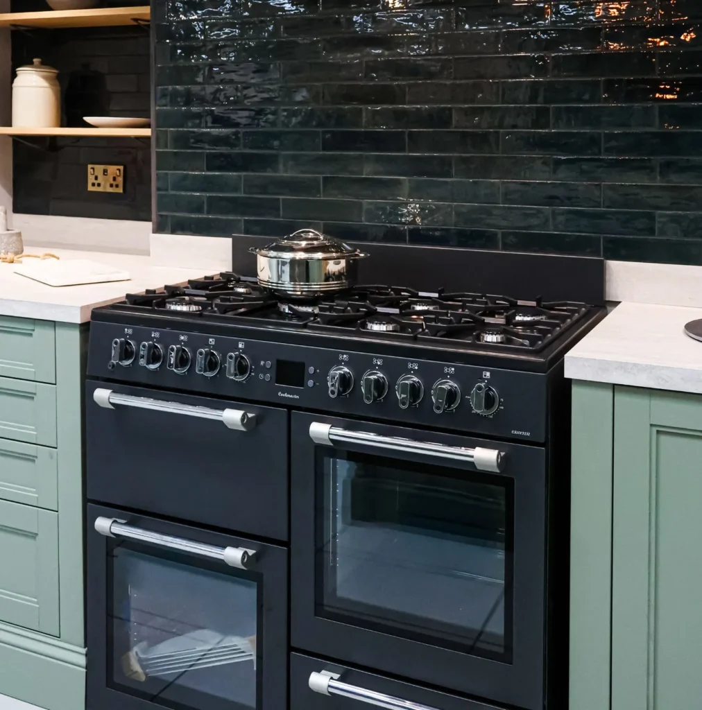 Oven cleaning in kent showing Black Range cooker against a black tiled kitchen and green units.